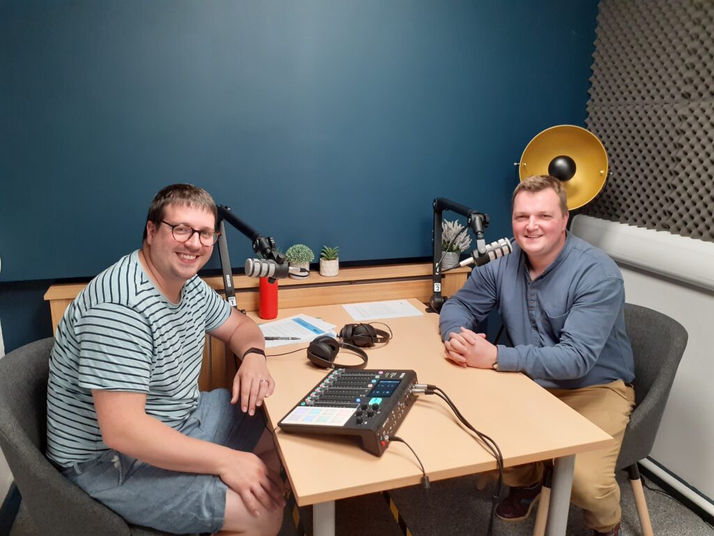 two dads sitting at a desk in a podcast studio, having a conversation