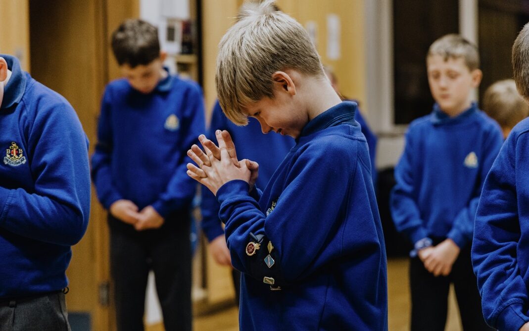 a junior section boys with his hands together praying
