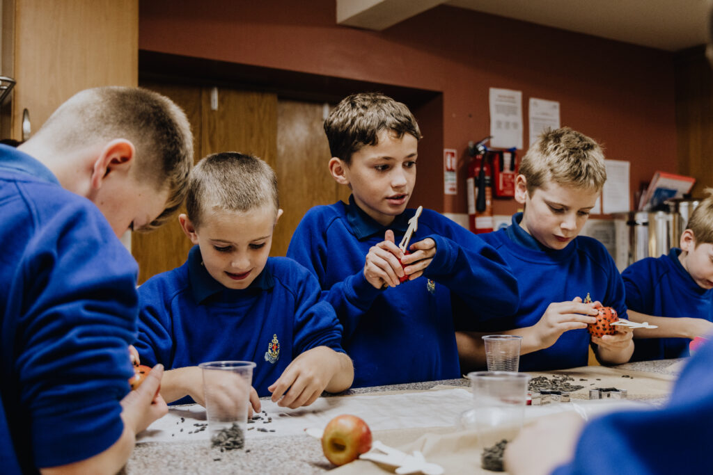 4 boys in blue BB uniform, working on a craft