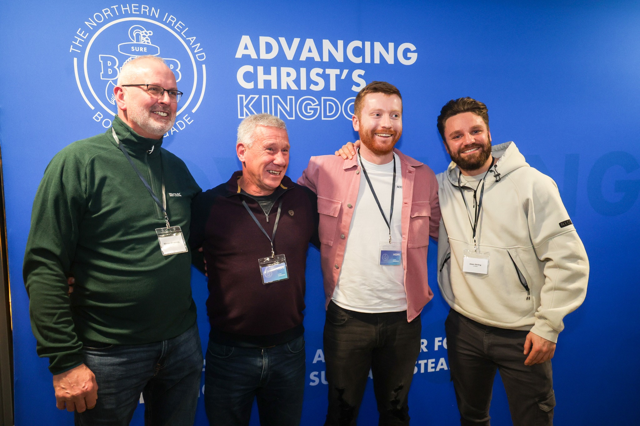 4 male BB leaders standing for a photo, in front on a blue sign that says 
